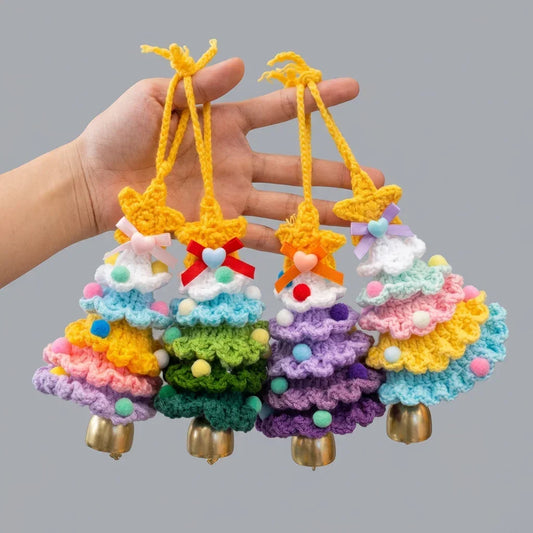 Hand holding four colorful Calivra Craft knitted Christmas tree hanging ornaments with bells