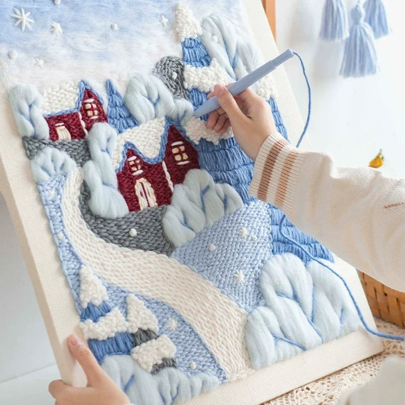 Hands working on a DIY wool felt photo frame embroidery kit with a snowy landscape design.