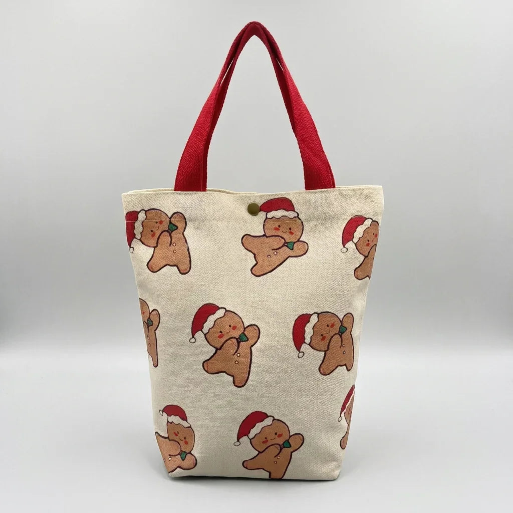 Christmas canvas tote bag with gingerbread man pattern and red handles.