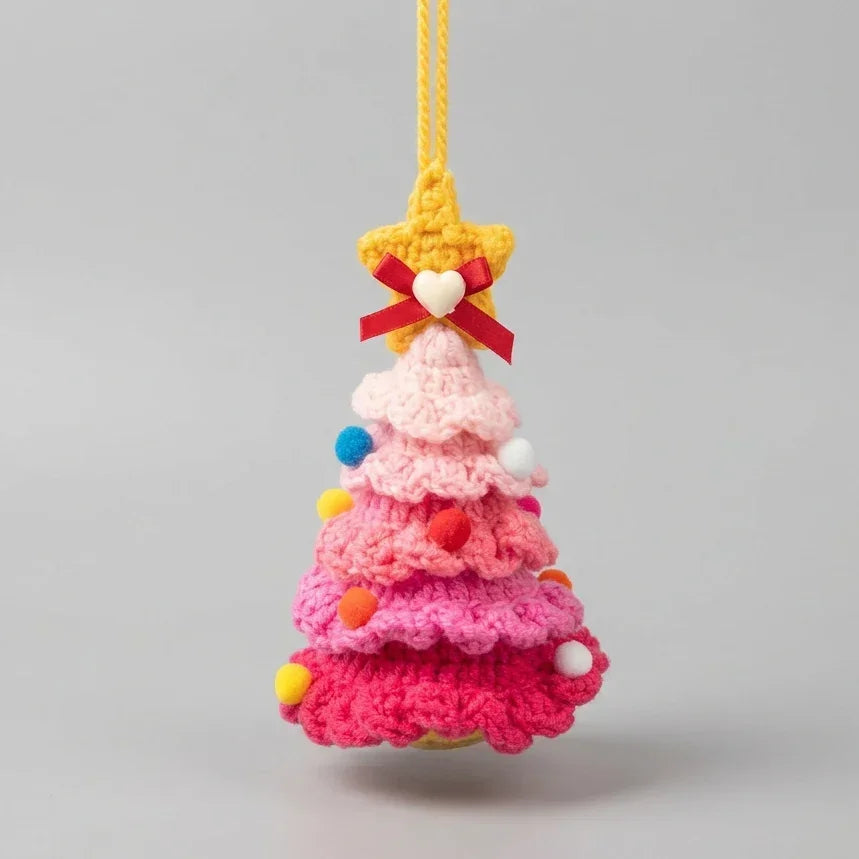 Pink knitted Christmas tree hanging ornament with a star topper and colorful pom poms.
