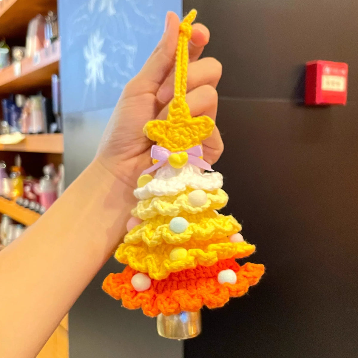 Handmade Calivra Craft knitted Christmas tree ornament in yellow and orange with a purple bow