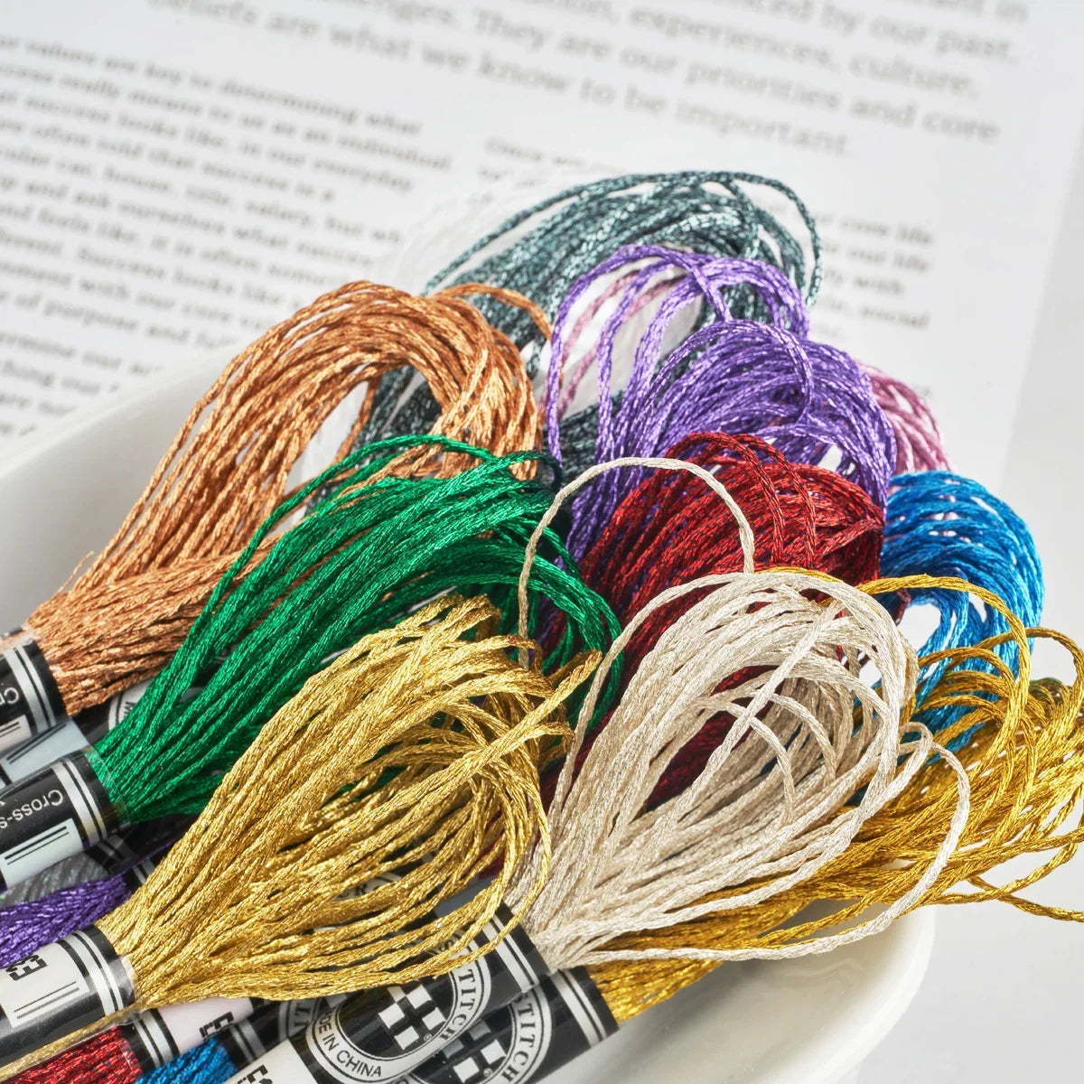 Colorful metallic embroidery floss skeins from Calivra Craft in a white bowl.