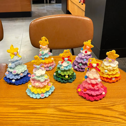 Set of colorful Calivra Craft knitted Christmas tree hanging ornament pendants on a wooden table.