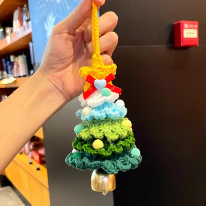 Hand holding a Calivra Craft knitted Christmas tree ornament with a yellow star and bell.
