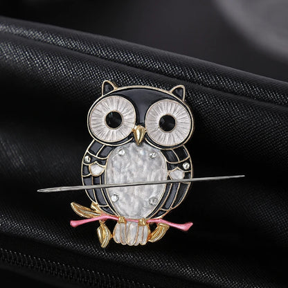 Decorative owl brooch with gemstones on a black background