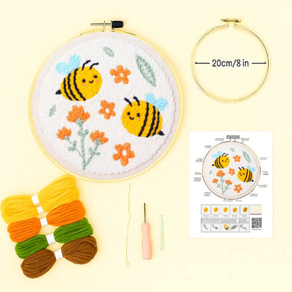 Embroidery hoop with bees and flowers, yarn balls, needle, and instruction sheet on a yellow background