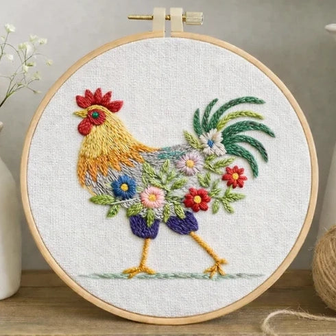 Colorful floral rooster embroidery in a wooden hoop on white fabric.