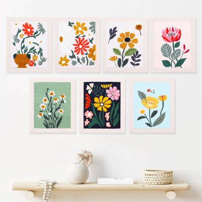 Set of seven colorful floral prints on a white wall above a wooden shelf.