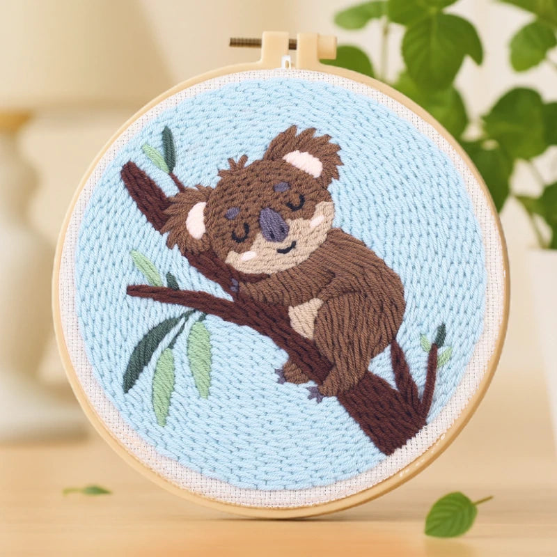 This cozy embroidery design shows an adorable koala peacefully napping on a tree branch. The soft shades of brown and green, set against a light blue background, create a calm and soothing feeling. Perfect for beginners, it’s a delightful piece to relax with on weekends or to gift someone who loves cute, heartwarming designs.