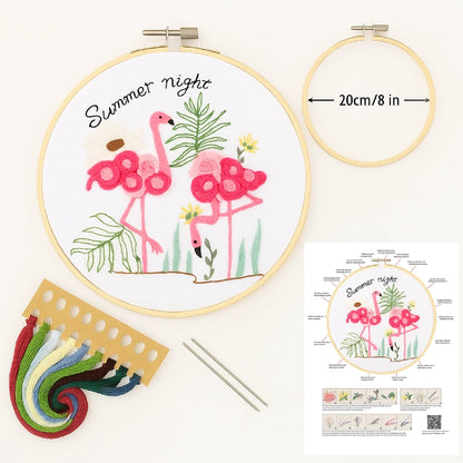Embroidery hoop with flamingo design, thread, needles, and pattern guide on a white background