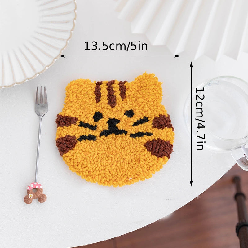 Yellow cat-shaped mat with dimensions on a white surface with a fork and glass.