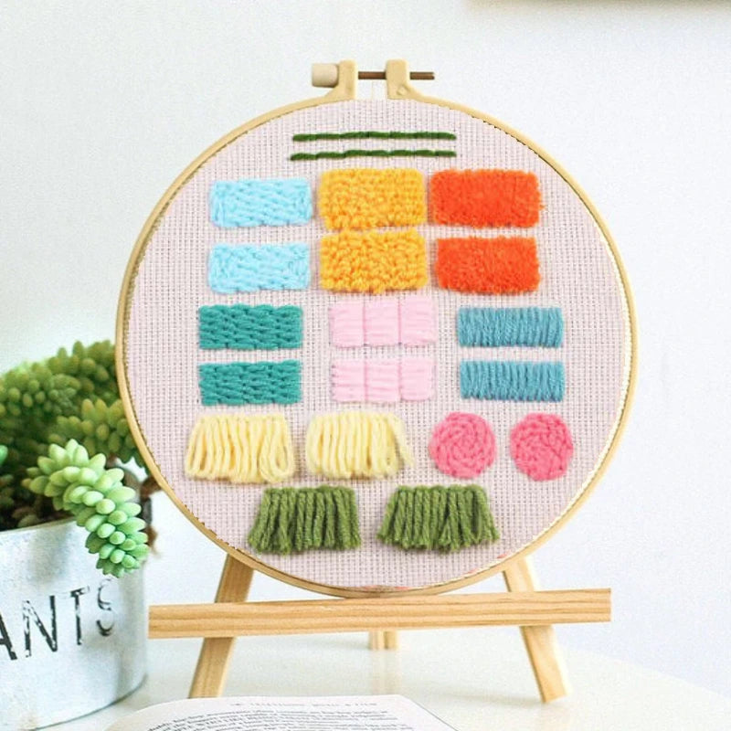 Features geometric shapes like blocks, stripes, and fringes in bright colours such as orange, pink, green, blue, and yellow. Perfect for practising flat stitches, loop stitches, and textured fills.