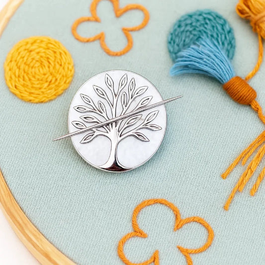 Pin with a stylized depiction of a girl with a pearl earring on an embroidered background