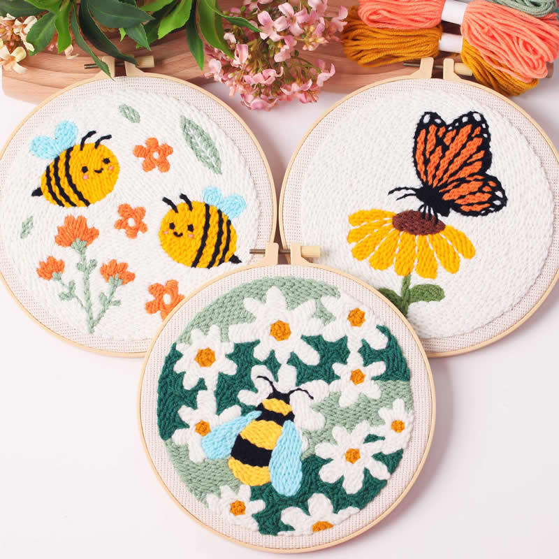 Three embroidered hoops with bees, flowers, and a butterfly on a white background.