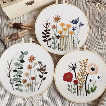 Three embroidery hoops with floral patterns on a textured fabric background