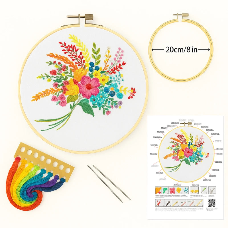 Embroidery hoop with colorful floral design, rainbow floss, needles, and instruction sheet on a white background.