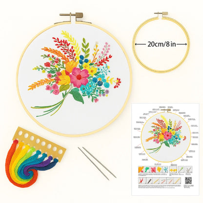 Embroidery hoop with colorful floral design, rainbow floss, needles, and instruction sheet on a white background.