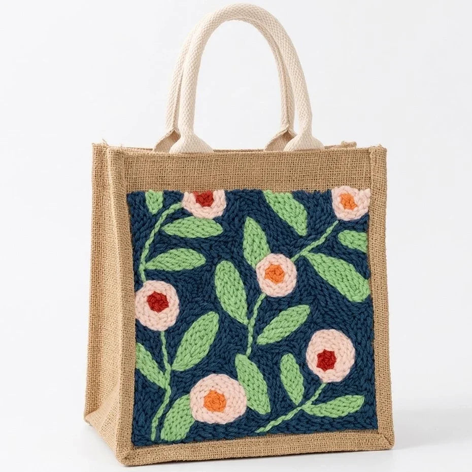 Small jute tote bag with colorful floral embroidery on a navy blue background.