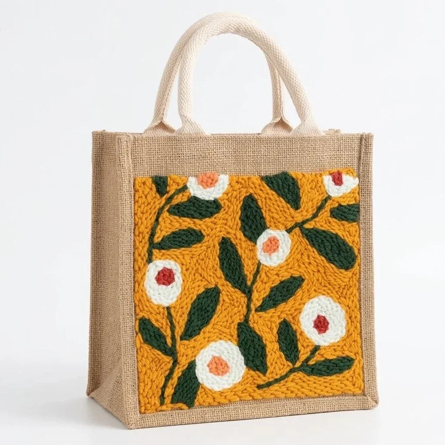 Handmade jute tote bag with colorful floral embroidery on yellow fabric patch.