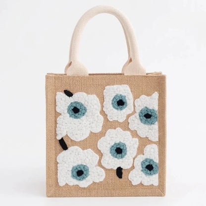 Small beige jute tote bag with white floral tufted embroidery pattern.