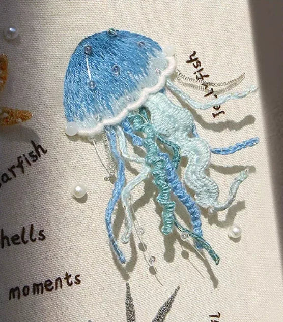 Embroidered blue and white jellyfish on ocean-themed DIY fabric kit.