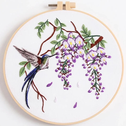 Embroidered hummingbird and purple wisteria flowers in a wooden hoop