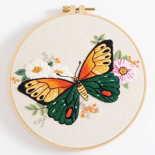 Hand embroidery of a colorful butterfly with white and pink flowers on cream fabric.