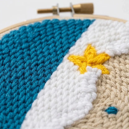 Close-up of a hand punch needle hoop featuring a blue, white, and beige landscape with a yellow star.