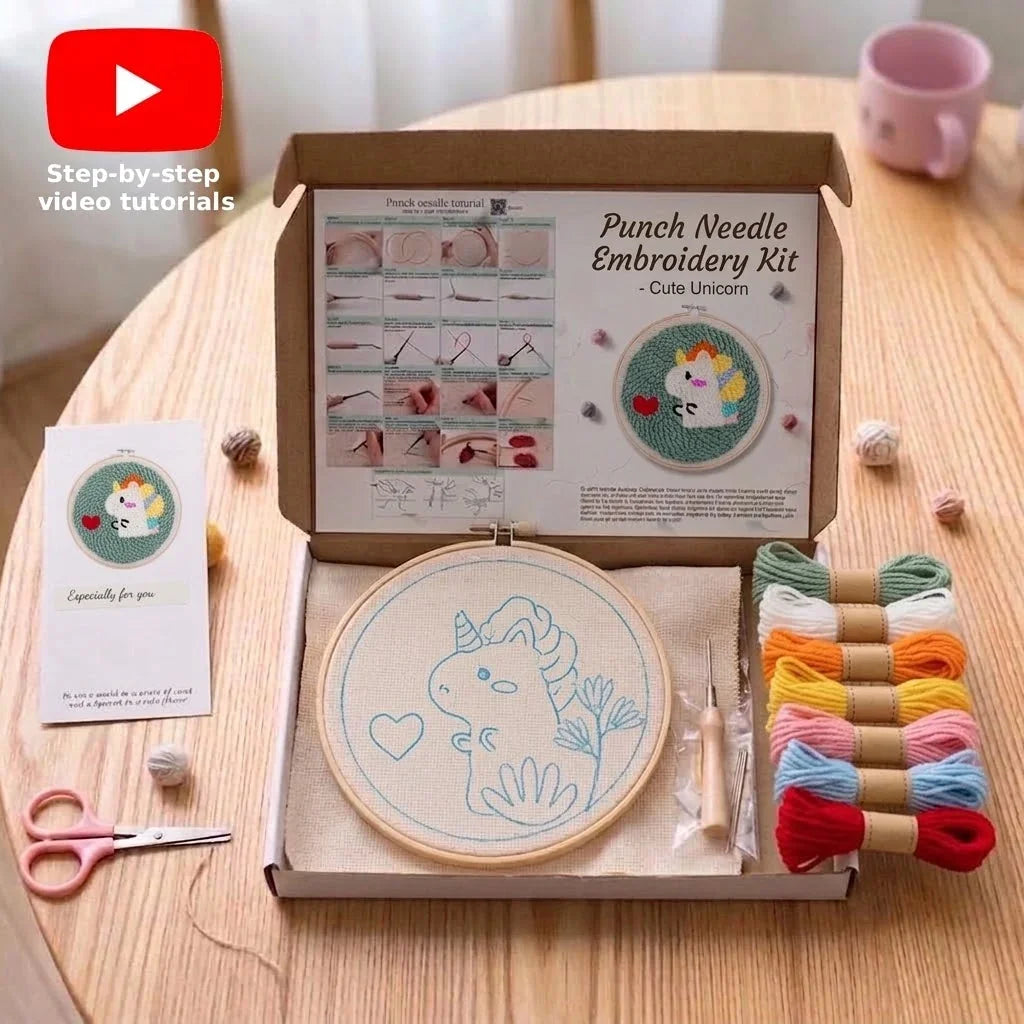 Punch needle embroidery kit with unicorn pattern, colorful threads, and tools on a wooden table.