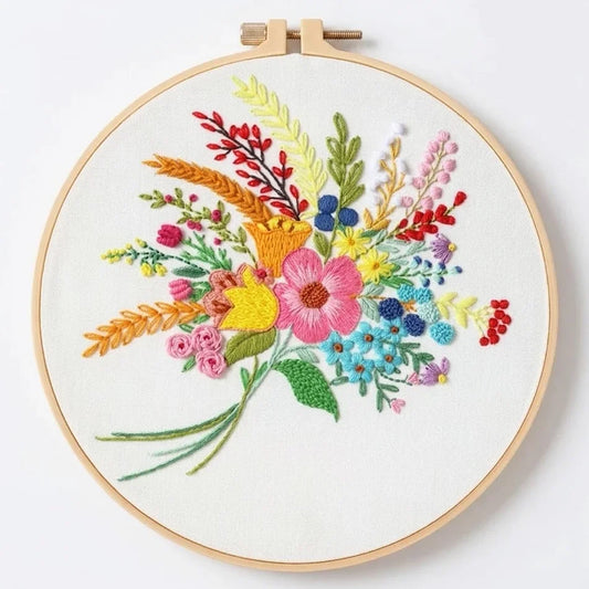 Colorful floral embroidery design in a wooden hoop on white fabric.