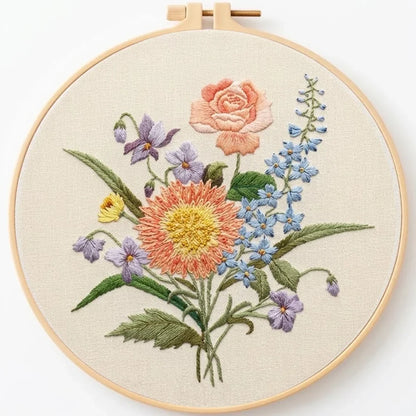 Hand-embroidered floral bouquet in a wooden embroidery hoop on off-white fabric.