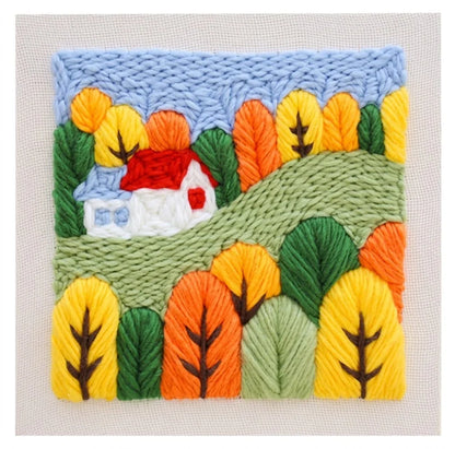 Punch needle embroidery kit featuring a colorful landscape with a red house and autumn trees.