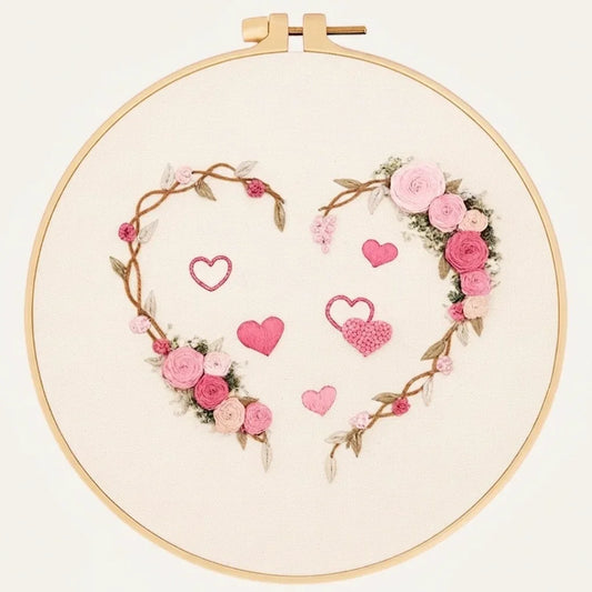 Hand embroidered floral heart wreath with pink roses and small hearts on white fabric.
