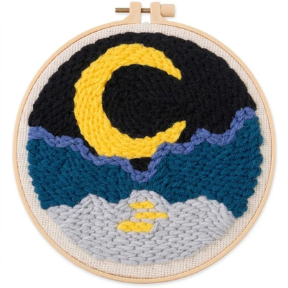 Handmade punch needle embroidery hoop art featuring a yellow crescent moon over blue mountains.