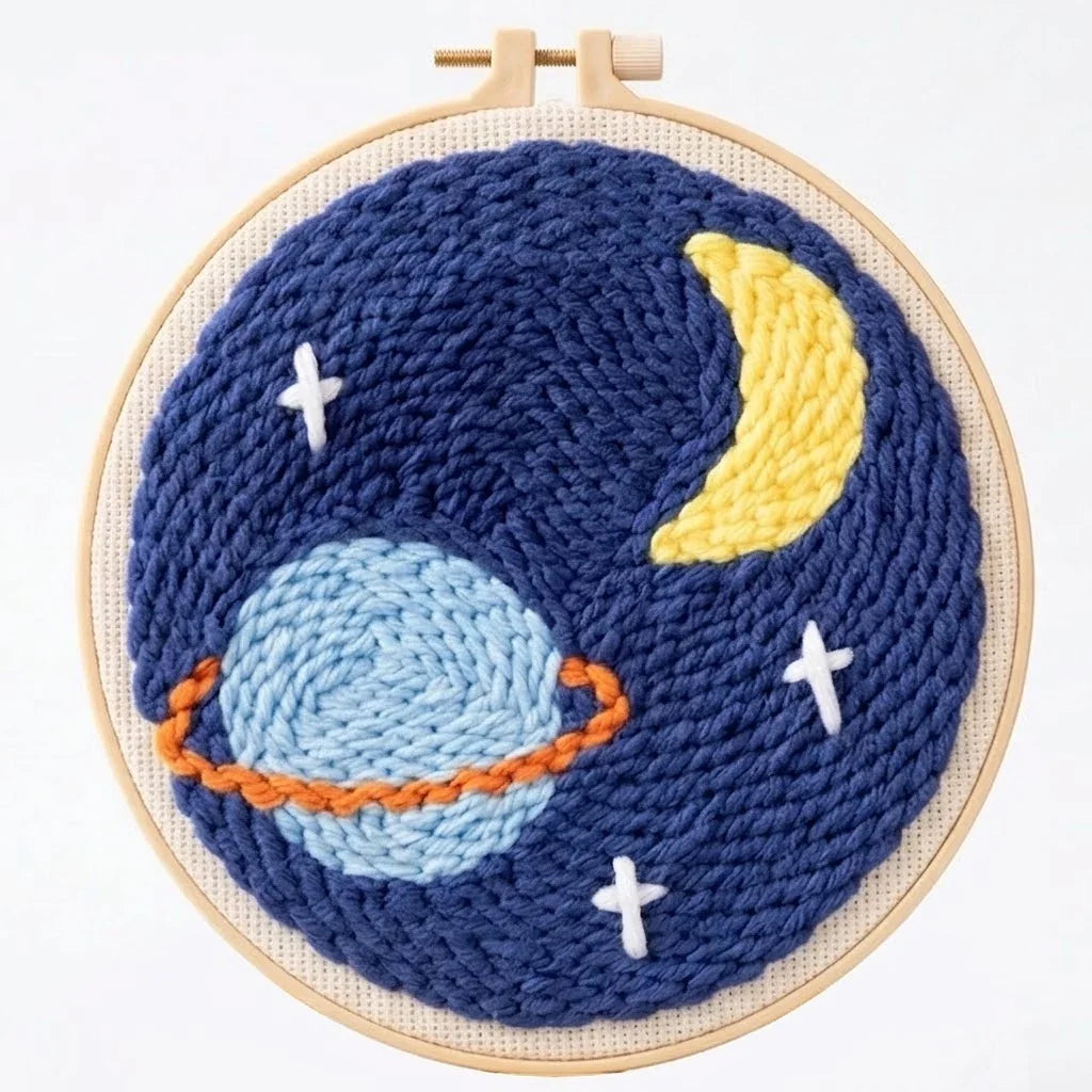 Handmade embroidery hoop art featuring a blue planet with rings, a crescent moon, and stars.