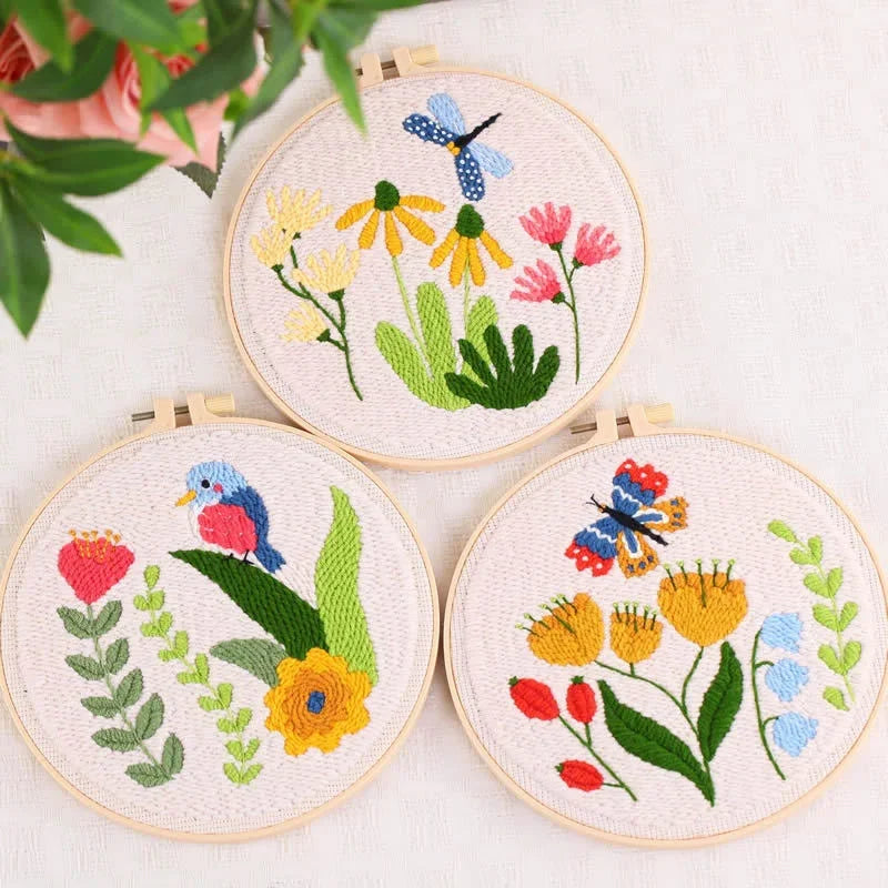 Three floral and animal themed punch needle hoops with colorful thread designs