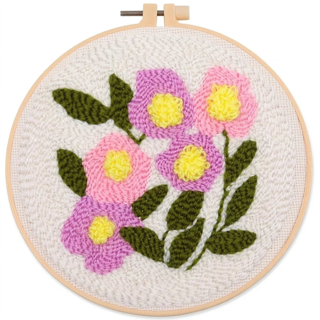 Hand-embroidered floral design with pink and purple flowers in a wooden embroidery hoop