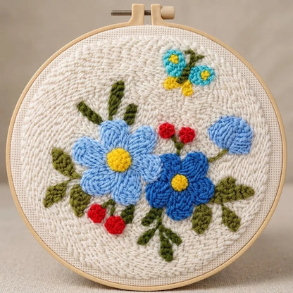 Hand-embroidered floral design with blue flowers and a butterfly in a wooden hoop.