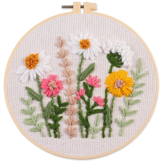 Hand-embroidered colorful spring flowers in a wooden embroidery hoop on white fabric.