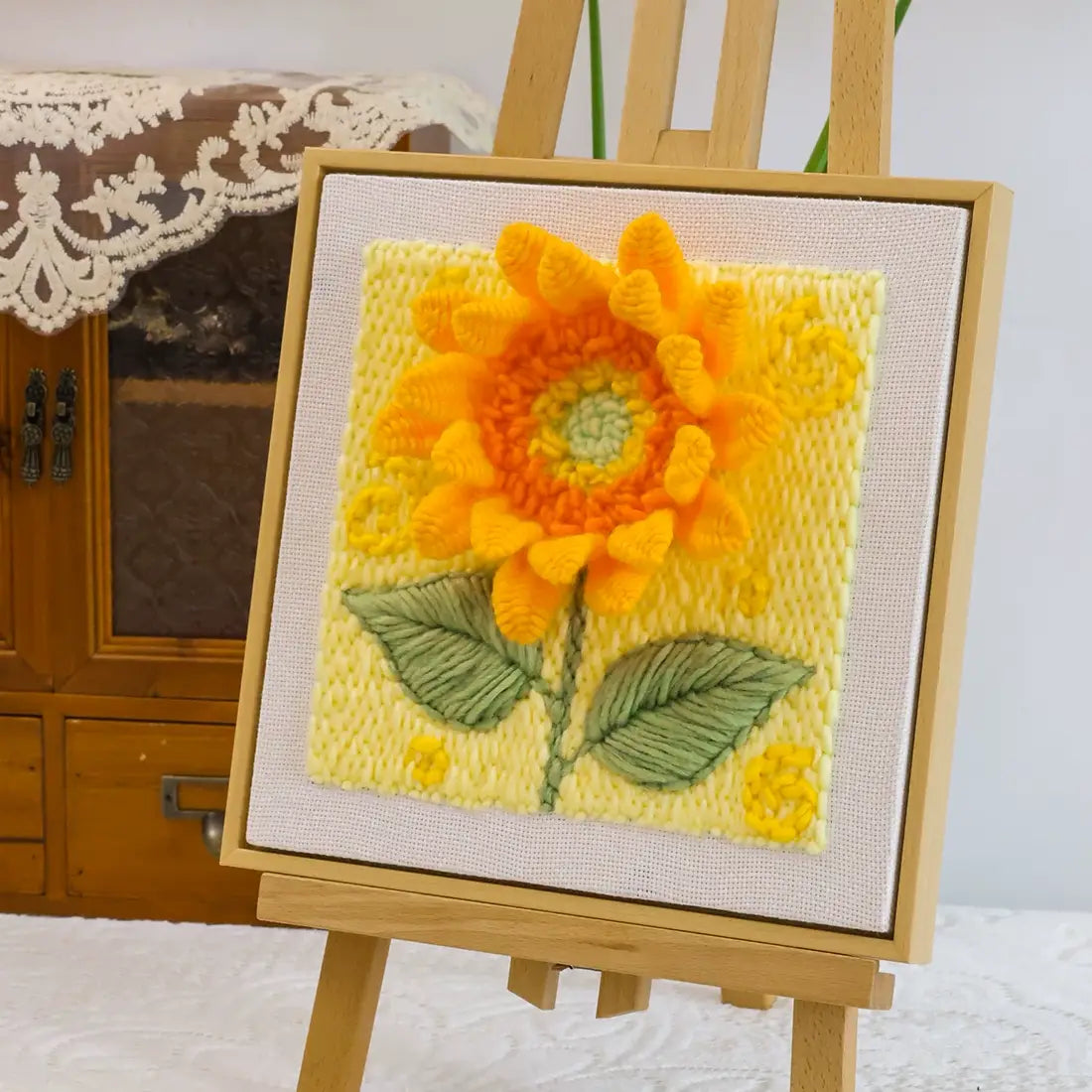 Completed Calivra Craft sunflower punch needle embroidery art on a small wooden easel