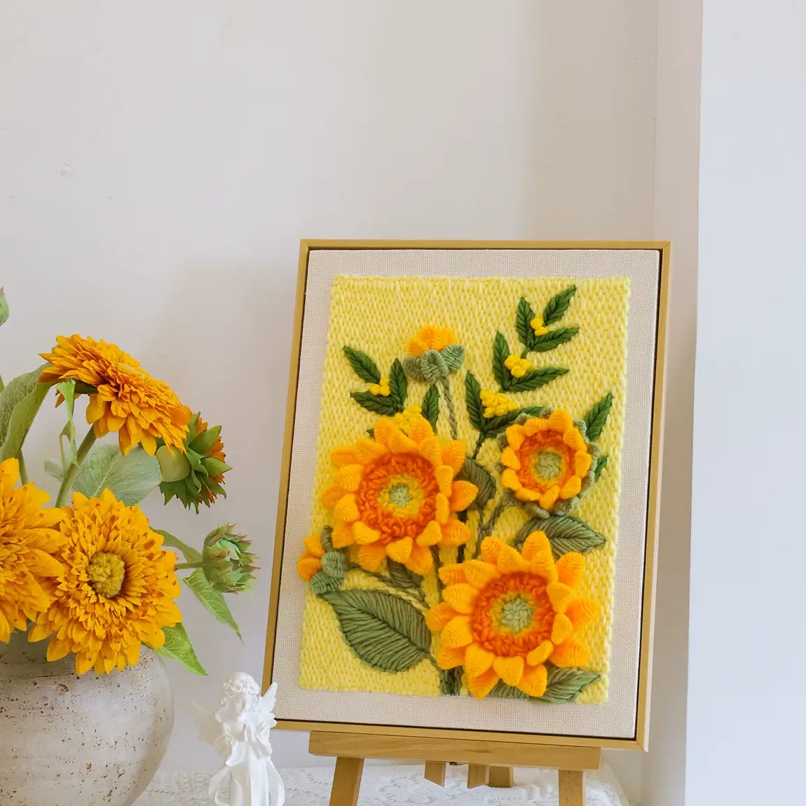 Yellow sunflower punch needle embroidery art displayed on a wooden easel.