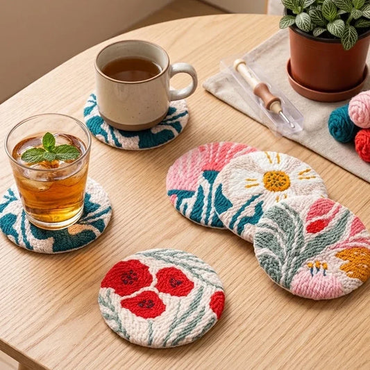 Set of six colorful hand-embroidered floral coasters on a wooden table with a mug and iced tea.